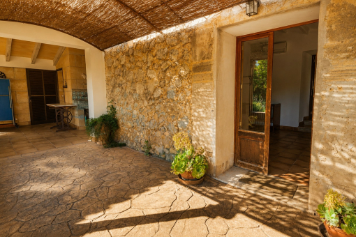 Covered patio with stone wall and plants