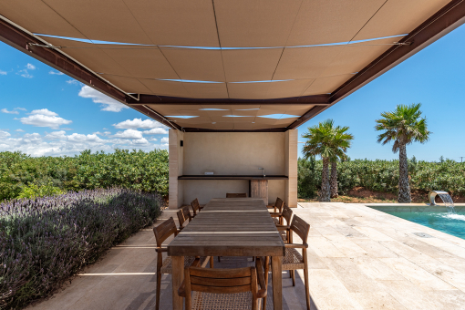 Terraza de la piscina con pérgola y zona preparada para una cocina exterior