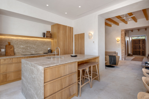 Open-plan kitchen with stone island and view into the living room
