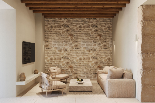Living room with stone wall and wooden beams – Mallorcan tradition in a modern interpretation