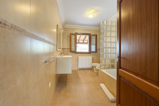 Amplio baño con bañera, luz natural y azulejos de buen gusto.