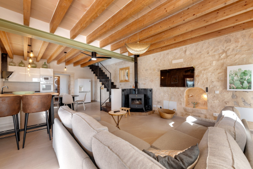 Bright living and dining area with wooden beams and wood-burning stove