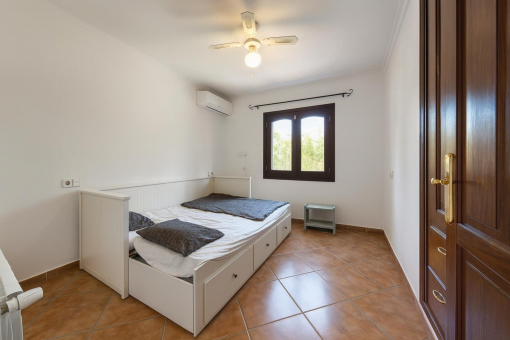 Dormitorio sencillo con ventana y ventilador