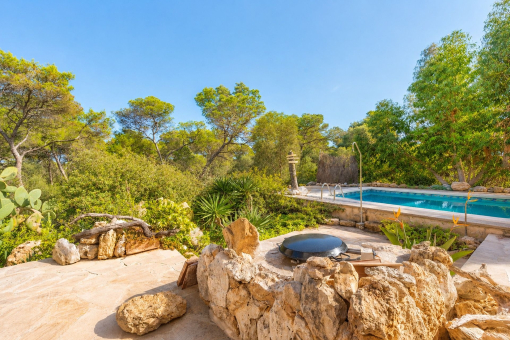 Piscina y terraza solárium rodeadas de vegetación mediterránea