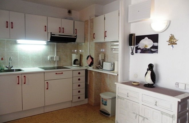 The white fitted kitchen with the entrance hall at the apartment